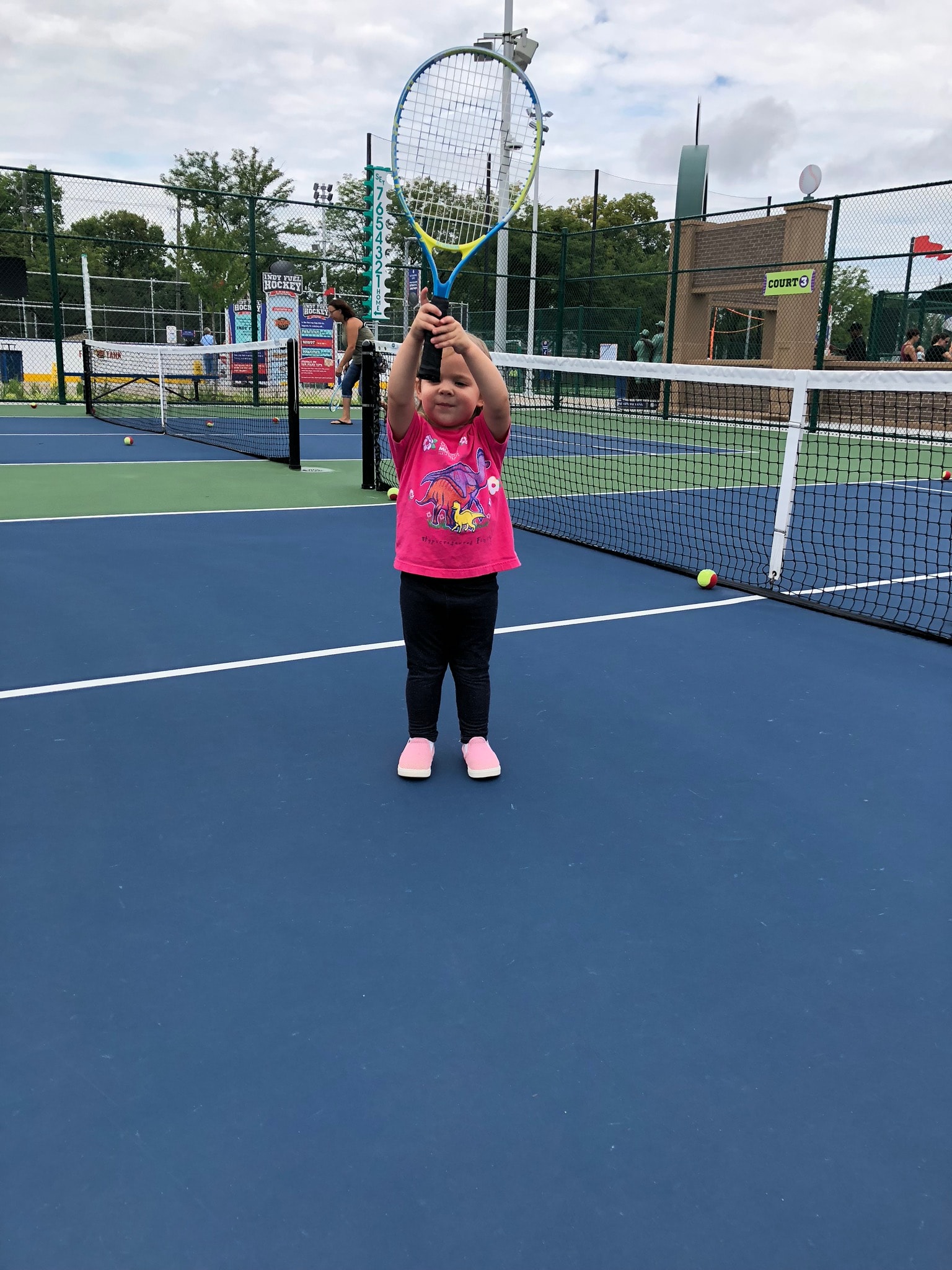 Young girl holding a racket overhead on an outdoor blue court